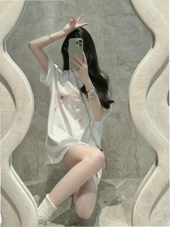 Cô gái xinh đẹp nhìn qua gương với điện thoại che mặt